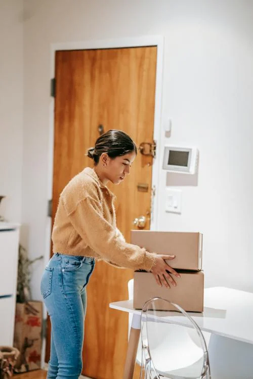 Side view of concentrated female in casual clothes preparing cardboard boxes for delivering