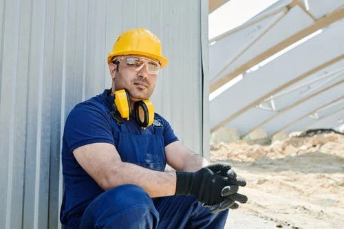 Man in Blue T-shirt and Yellow Helmet Sitting on Ground