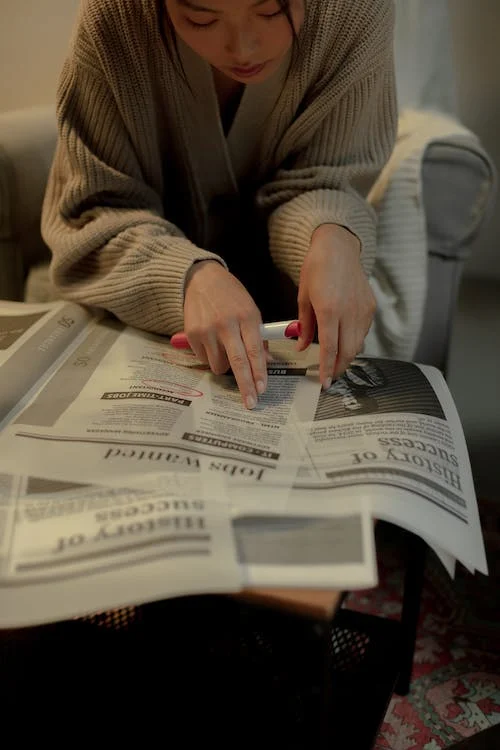 Sitting woman looking for job in newspaper